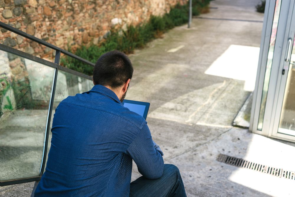 Back of man checking digital tablet on stairs