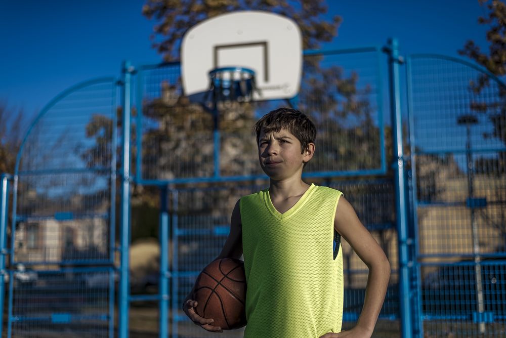 Teenage boy holding a basketball on a court