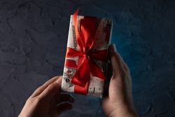 Man holding Christmas gift near tree