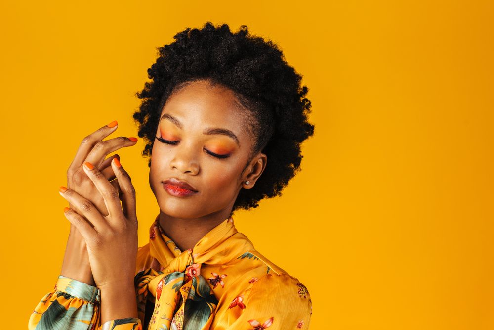 Elegant Black woman holding her hands to her face with her eyes closed