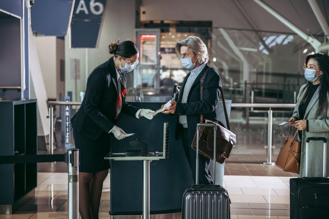 Flight attendant at check in counter assisting passengers during pandemic