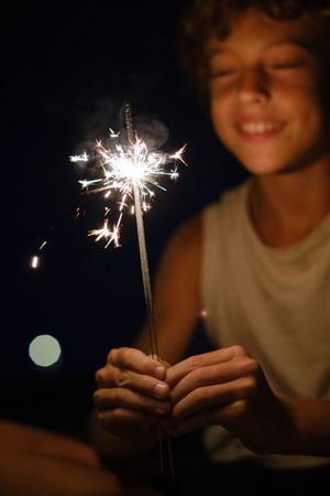 Smiling boy celebrating holiday with sparklers