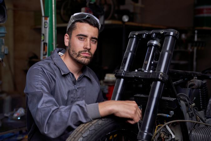 Confident man sitting near motorcycle in garage