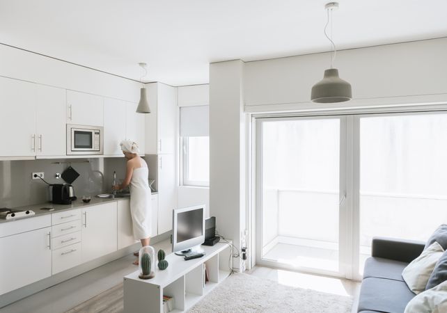 Pensive serene woman having refreshment with water in comfortable kitchen