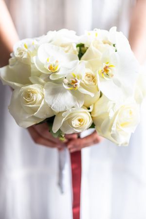 Bride holding wedding bouquet with roses and orchids