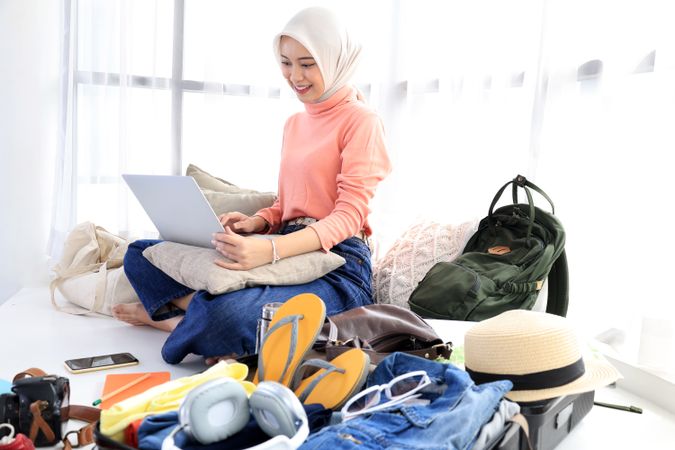 Asian Hijab Muslim Woman Prepare Things into Baggage for Vacation trip at Home.