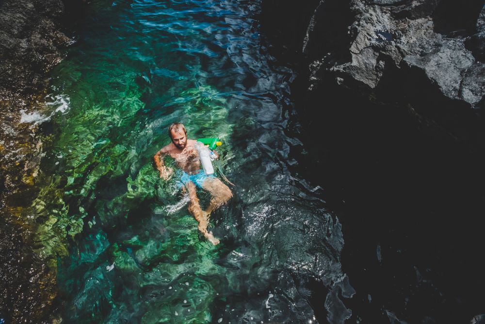 Man swimming in water with rubbish