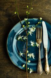 Spring table setting with blooming tree branch on ceramic blue plate
