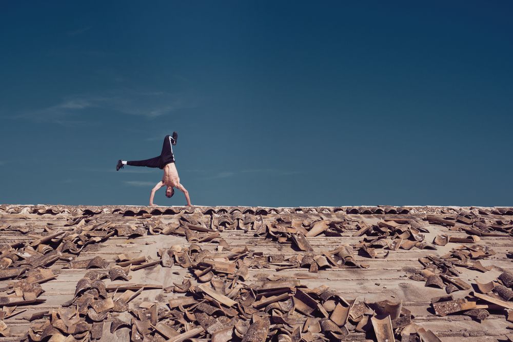 Unrecognizable man performing handstand element of freestyle dance on roof