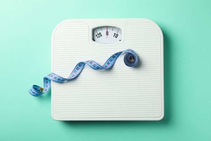Scales and measuring tape on mint background. Weight loss concept