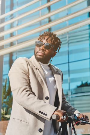 Stylish Black man with scooter near building