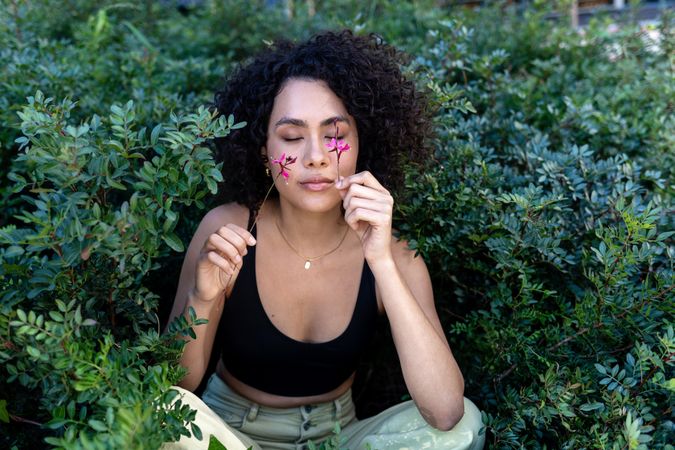 Beautiful young woman with afro hair surrounded by flowers with eyes closed