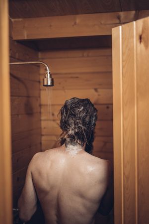 Man taking shower in wooden bathroom