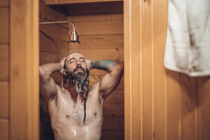 Man taking shower in wooden bathroom