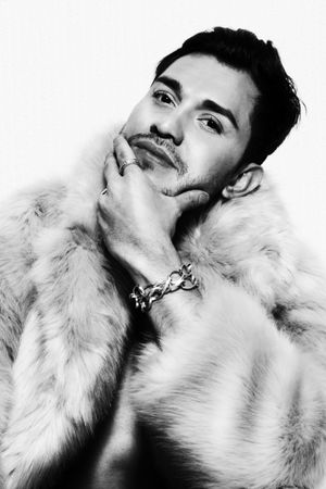 Grayscale portrait of man wearing fur touching his beard