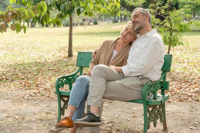 Male and female older couple relaxing together on park bench