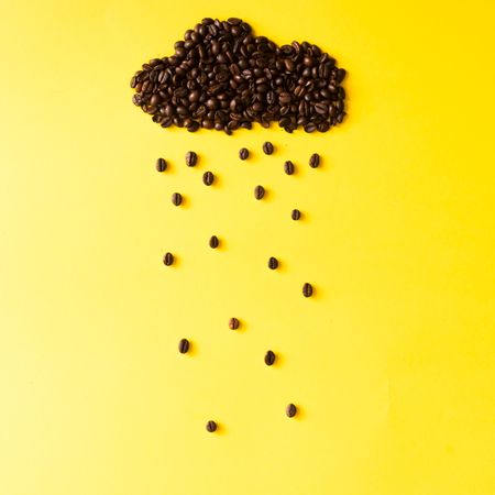 Coffee beans in shape of rainy cloud on yellow background