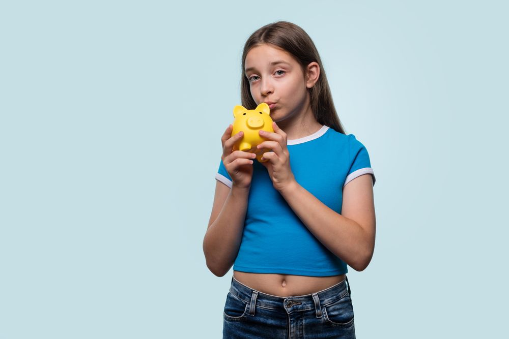 Girl kissing a yellow piggy bank