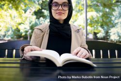 Middle Eastern woman sitting at park table with book 0K66Mb