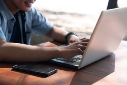 Close Up Asian Young businessman work at outdoor with laptop. Concept of remote and freelance work. Young successful man wearing casual blue cloth.