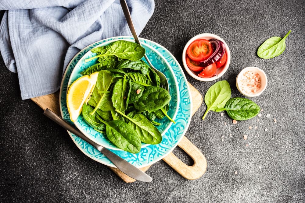 Top view of fresh spinach salad with lemon slice