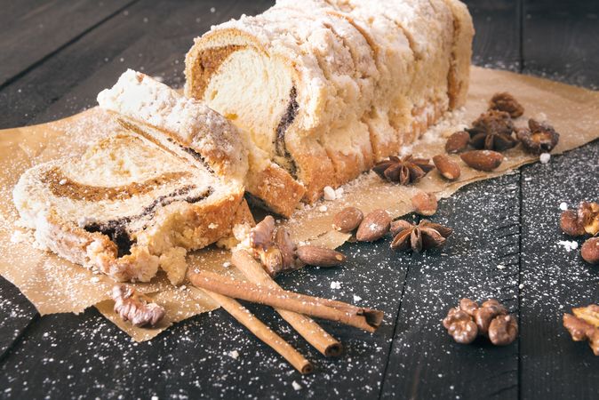 Sliced pound cake with nuts on parchment paper on rustic wooden table