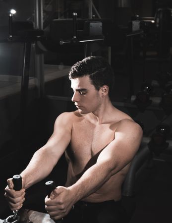young fitness man doing machine weights in the gym