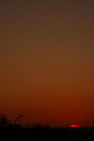 Dark orange skyline with factory smoke twilight hour