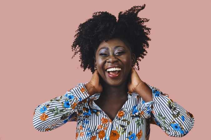 Portrait of Black woman with a happy expression and both hands to her head