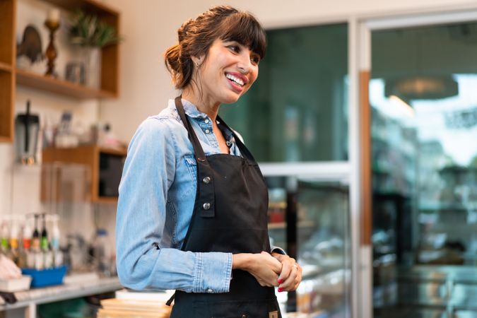 Happy coffee shop owner  in apron welcoming customers