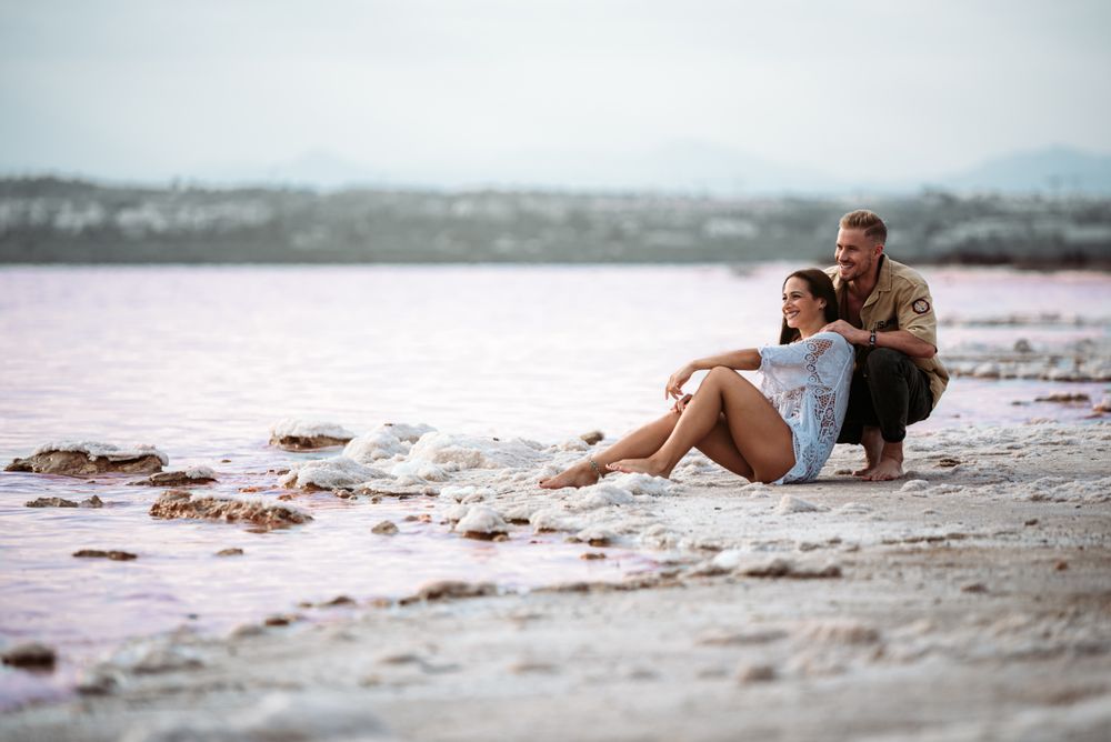 adorable couple sitting on an amazing beach with pink water