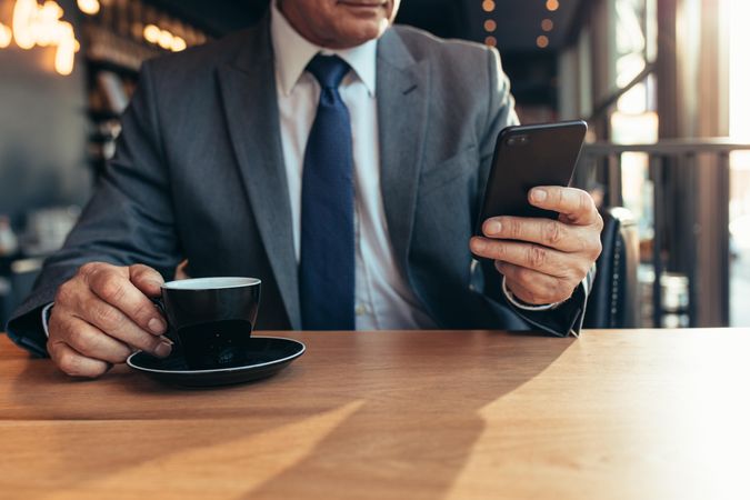 Older businessman texting on mobile phone at coffee shop