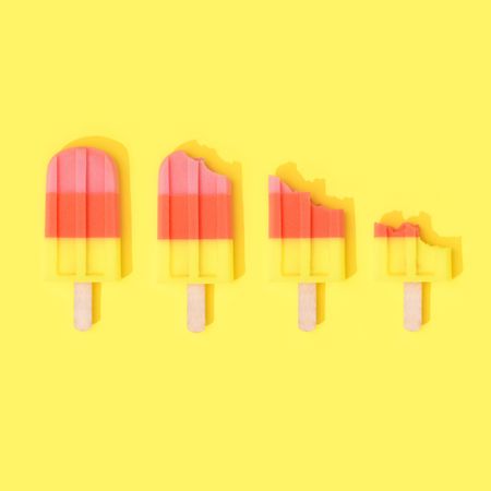 Row of ice cream popsicles on bright yellow background