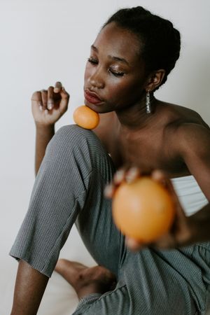 Woman wearing red lipstick holding orange fruit