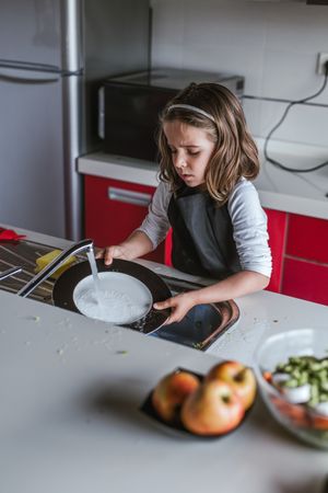 Girl washing dishes in kitchen