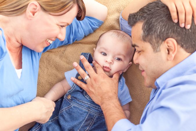 Young Couple Laying With Their Infant On A Blanket