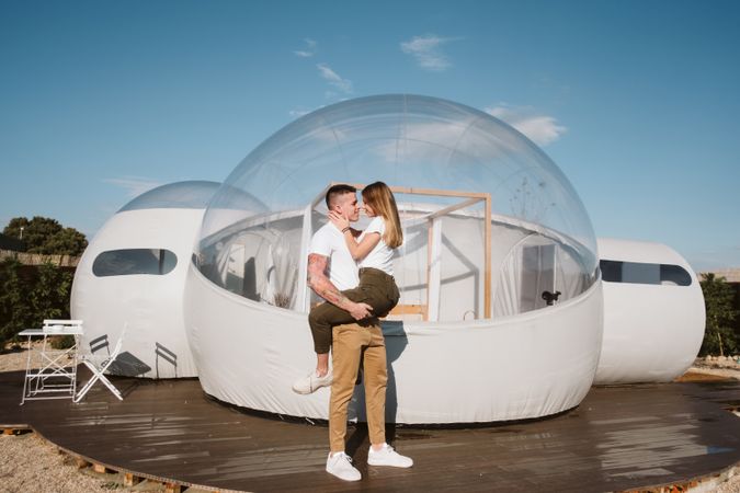 Affectionate couple kissing near bubble hotel