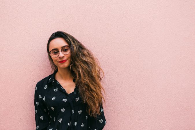 Smiling young woman against pink wall