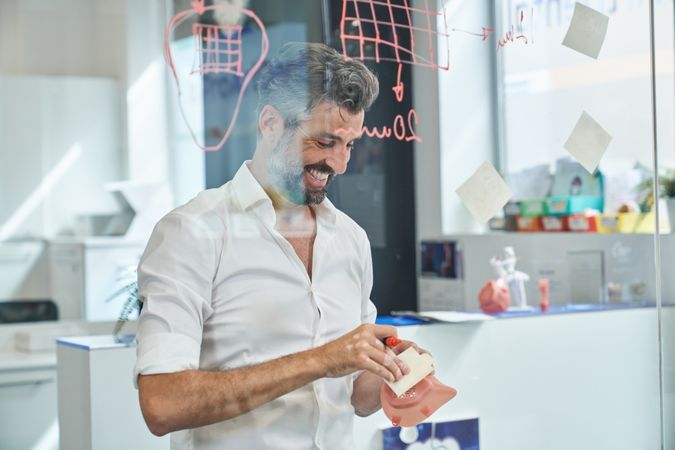 Smiling worker preparing stickers near glass wall