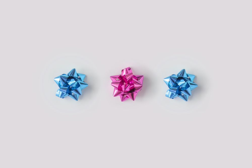 Row of plastic pink decorative gift bows bordering light background
