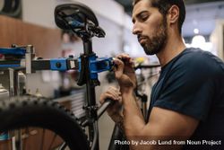 Worker adjusting the seat of a bicycle in a shop 49AlB4