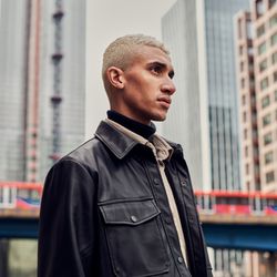 Young man standing among tall buildings looking off in the distance