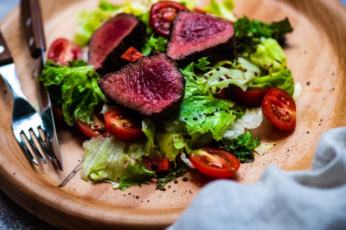 Steak salad with fresh lettuce and tomatoes served with silverware