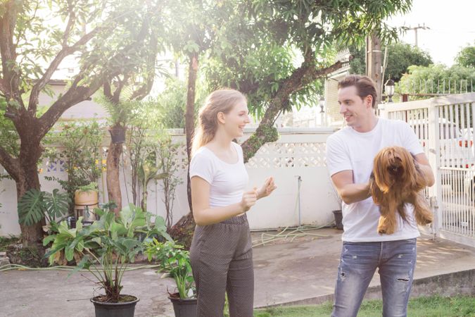 Husband and wife playing with dog in backyard