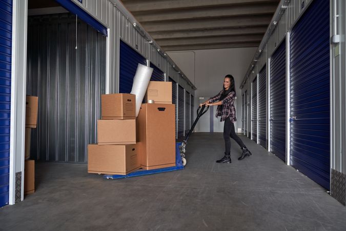 Content woman rolling carton boxes into container