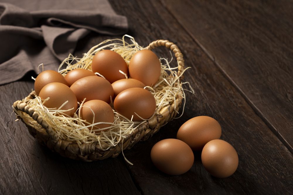 Basket with brown chicken eggs goes up the table.