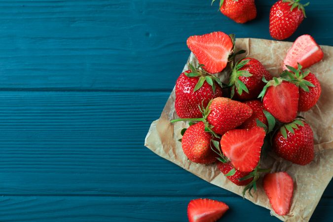 Fresh strawberries and parchment on wooden background, space for text and top view. Summer sweet fruits and berries