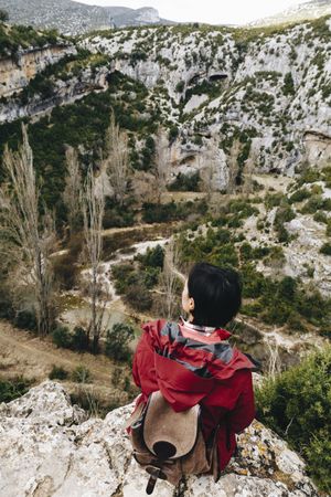 Woman with backpack on high cliff