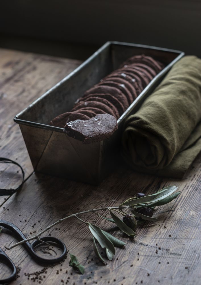 Dry olive twig near chocolate cookies and towel