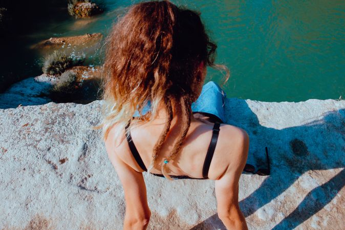 Anonymous woman on cliff looking at water